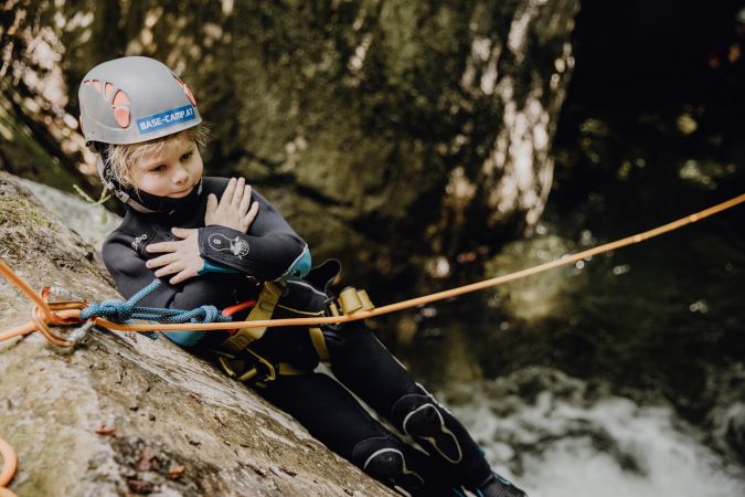 Kinder spielen im Wildwasser einer felsigen Schlucht