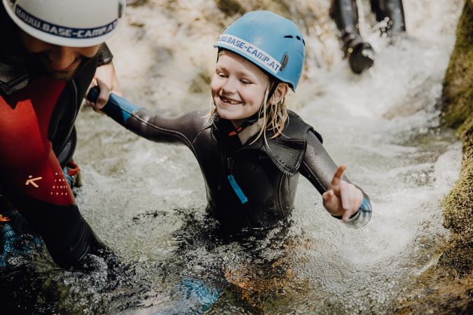 Kinder rutschen beim Canyoning durch eine Wasserschlucht