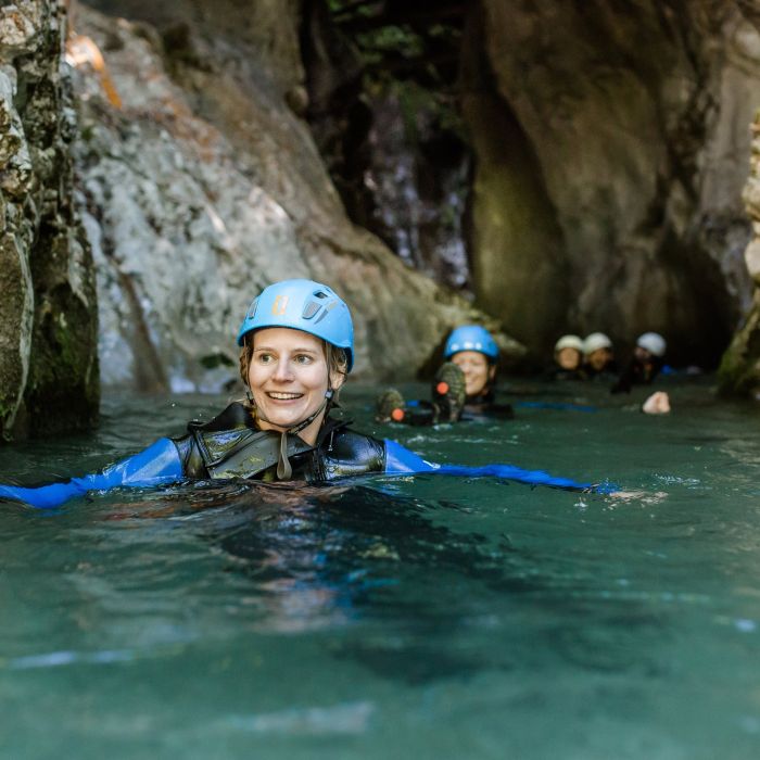 Teilnehmer schwimmt durch eine enge Felsenschlucht beim Canyoning